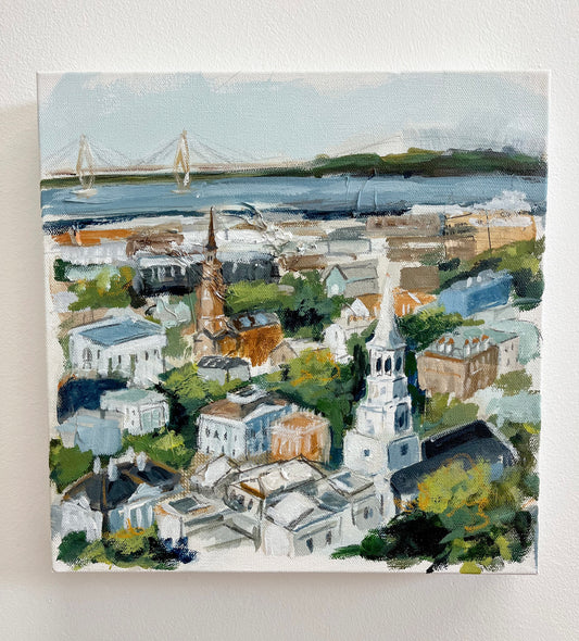 Christy Holmes 12x12 acrylic canvas of Charlestons cityscape with churches, houses, greenery, and a distant bridge.