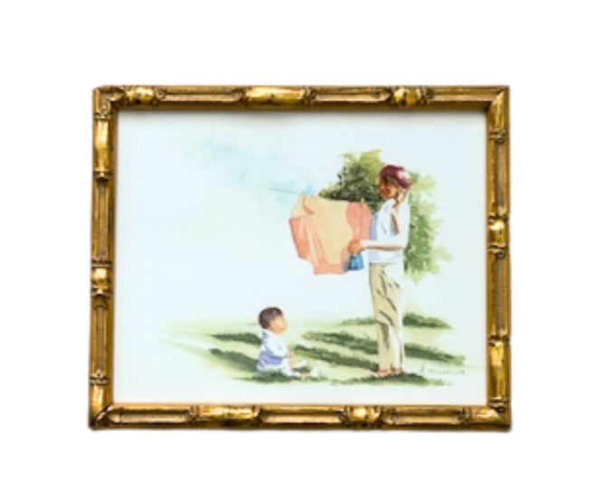 A Keri Misawa framed 8x10 wall art print shows an adult hanging laundry outdoors as a child sits on the grass nearby.