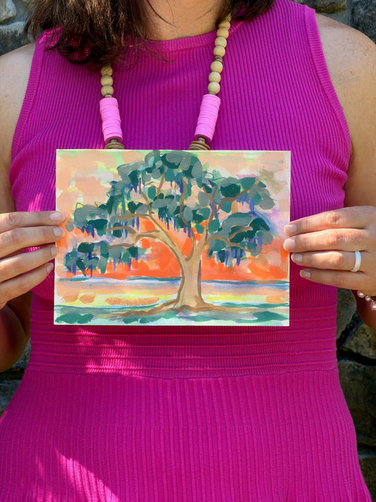 A person in a pink dress holds an original watercolor tree art from Elizabeth Sheats Art & Design.