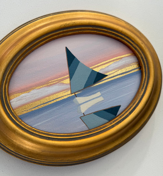 Oval coastal artwork of a stylized sailboat on water at sunset in a gold frame.
