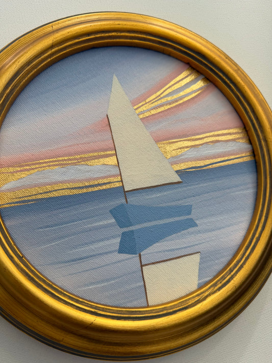 A circular coastal painting of a stylized sailboat on water at sunset with 24K gold leaf accents, in a gold frame.