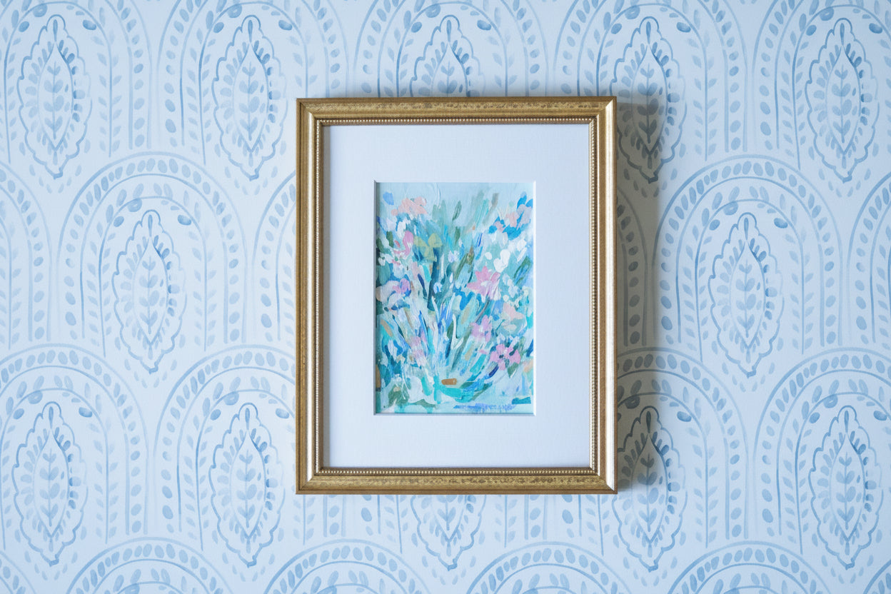 Framed artwork with a floral design on a blue patterned wall