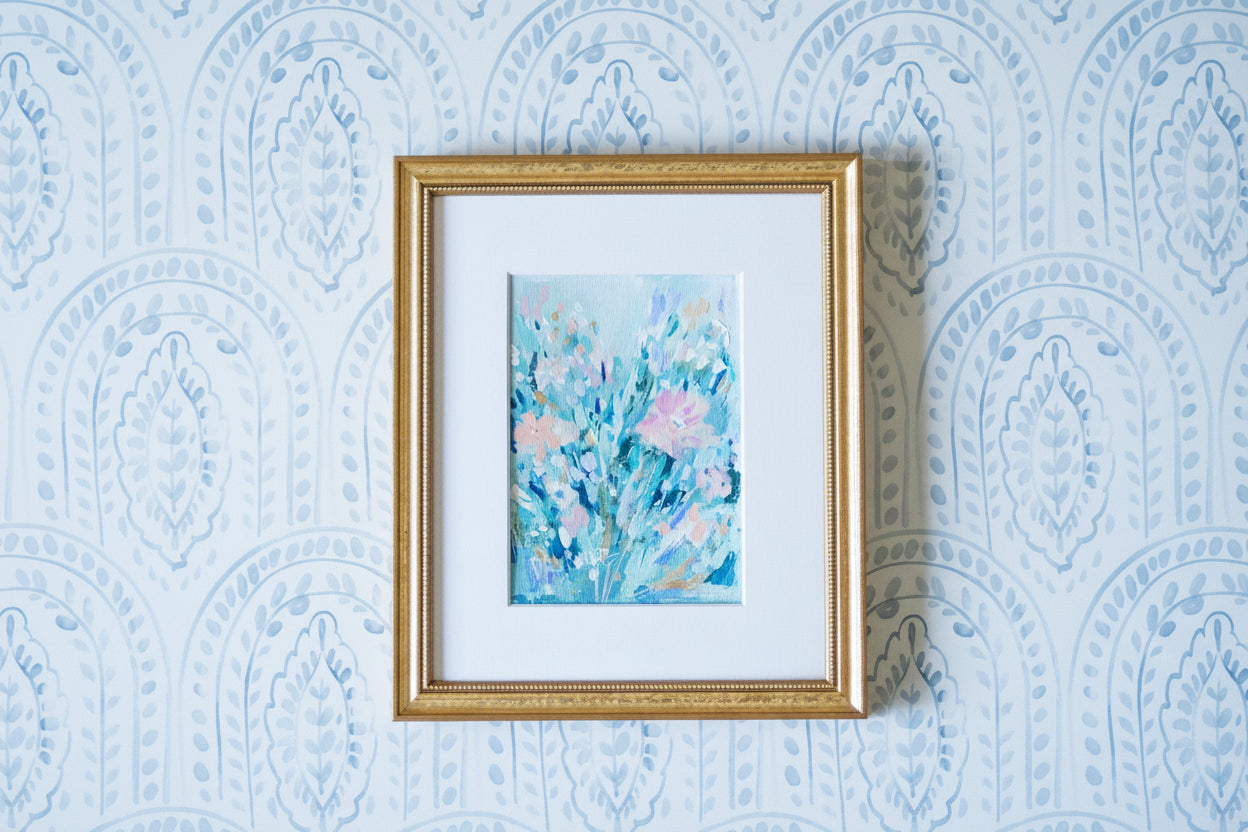 Framed artwork with floral design on a blue patterned wall