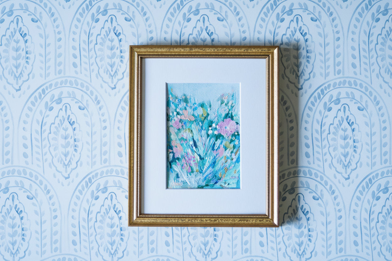 Framed artwork with floral design on a blue patterned wall