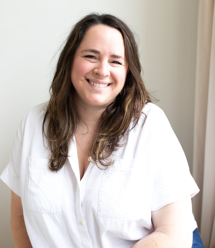 A smiling woman with long brown hair wearing a white collared shirt.