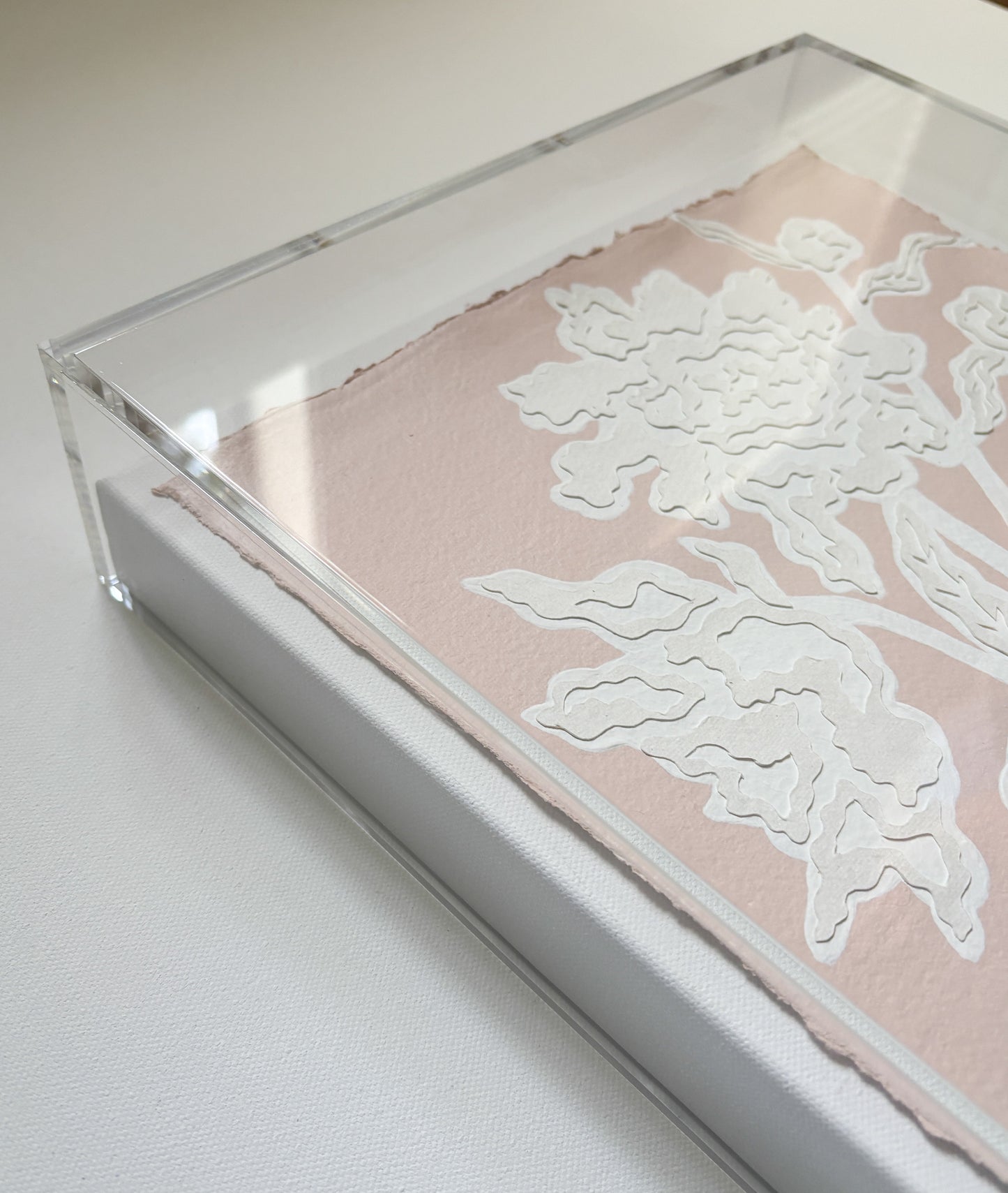 A framed white floral collage on cotton rag paper by Kendal Blanchard Art, enclosed in an acrylic box frame.