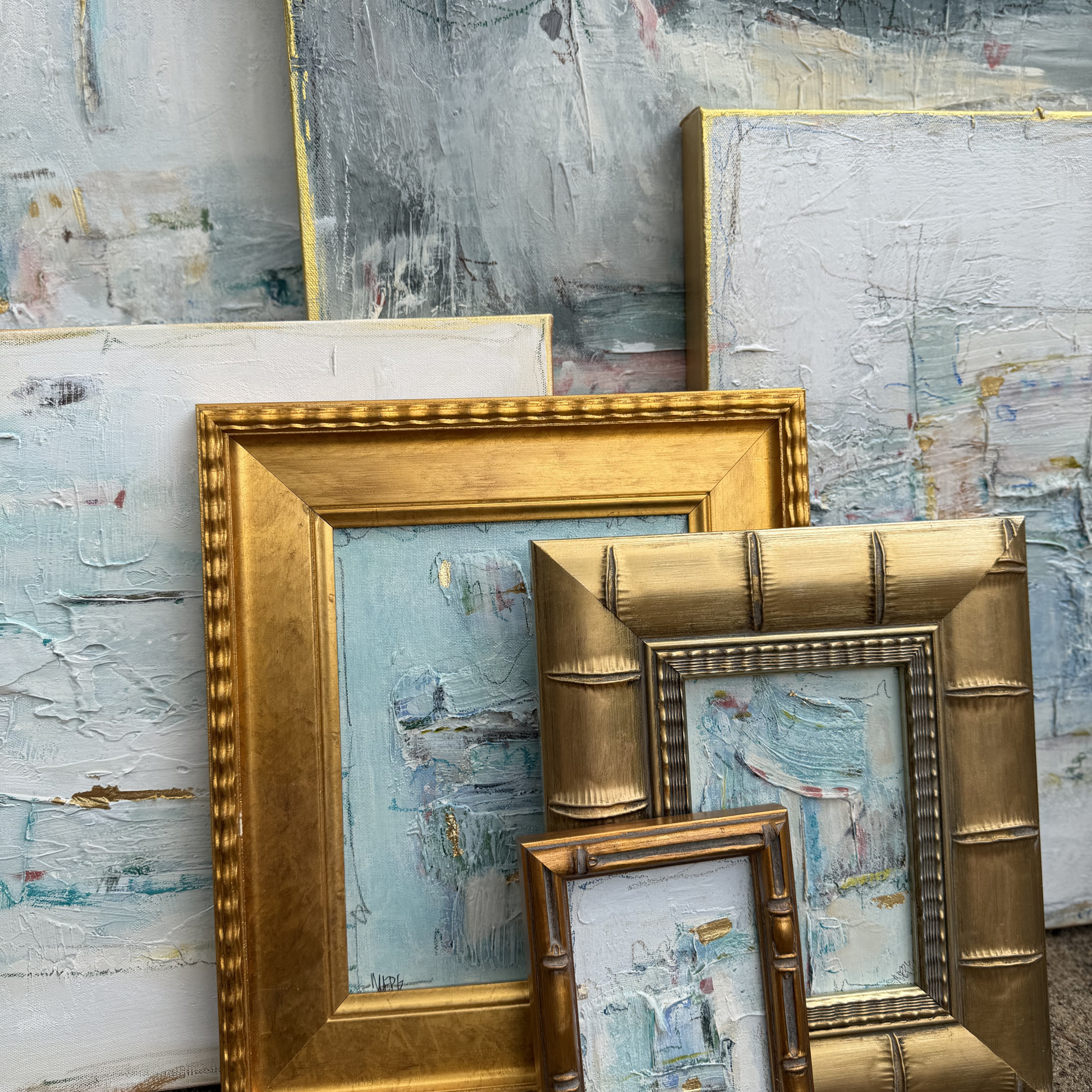 Megan Guidry’s abstract paintings in gold frames evoke glacial lakes with textured blue and white brushstrokes.