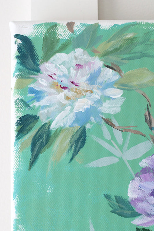 Close-up of a painted white flower and green leaves on canvas by Elizabeth Alice Studio, inspired by Chinese brushwork.