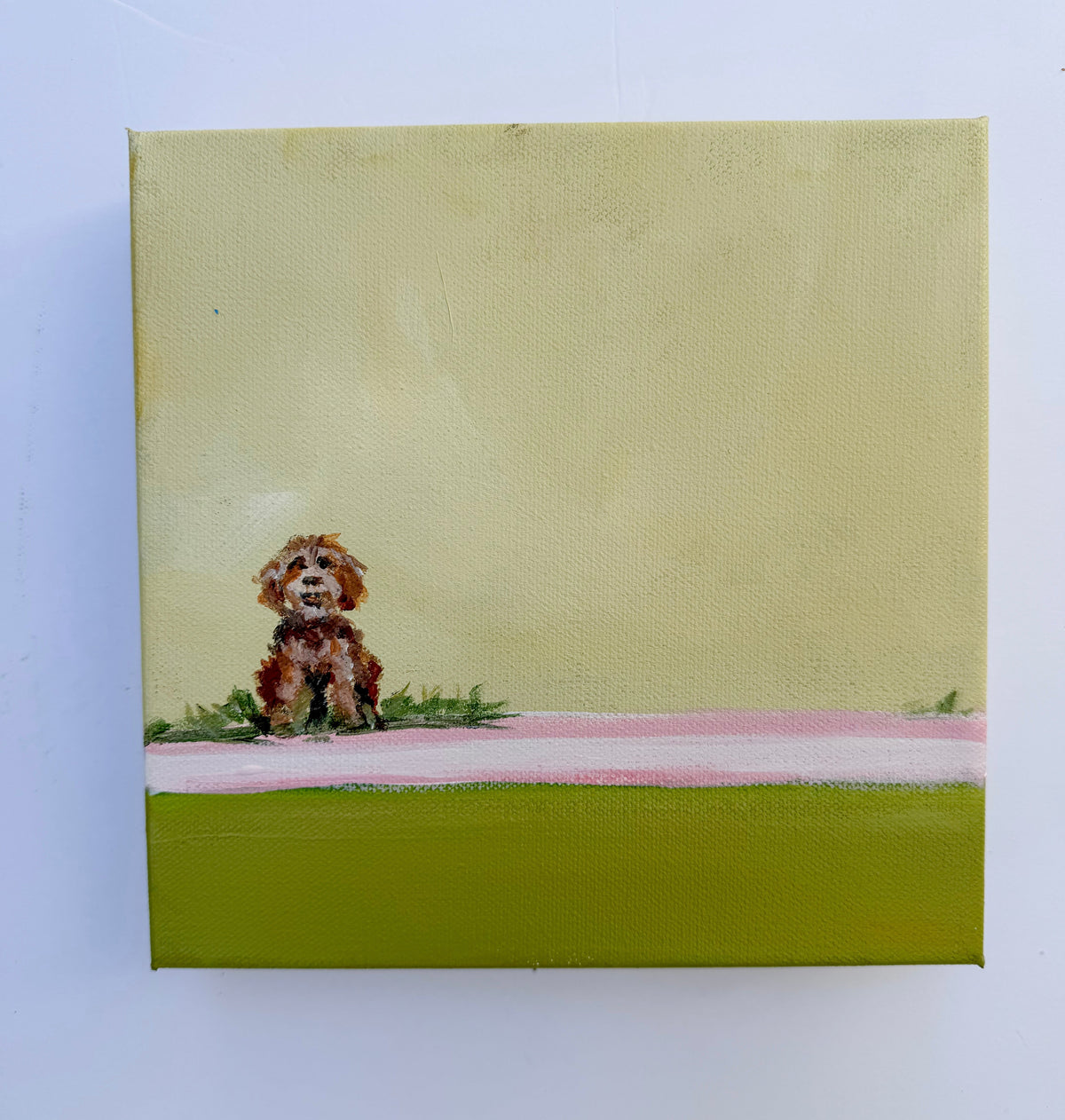 Small brown dog sitting in grass on a light yellow background; an original acrylic painting from the Unleashed collection.