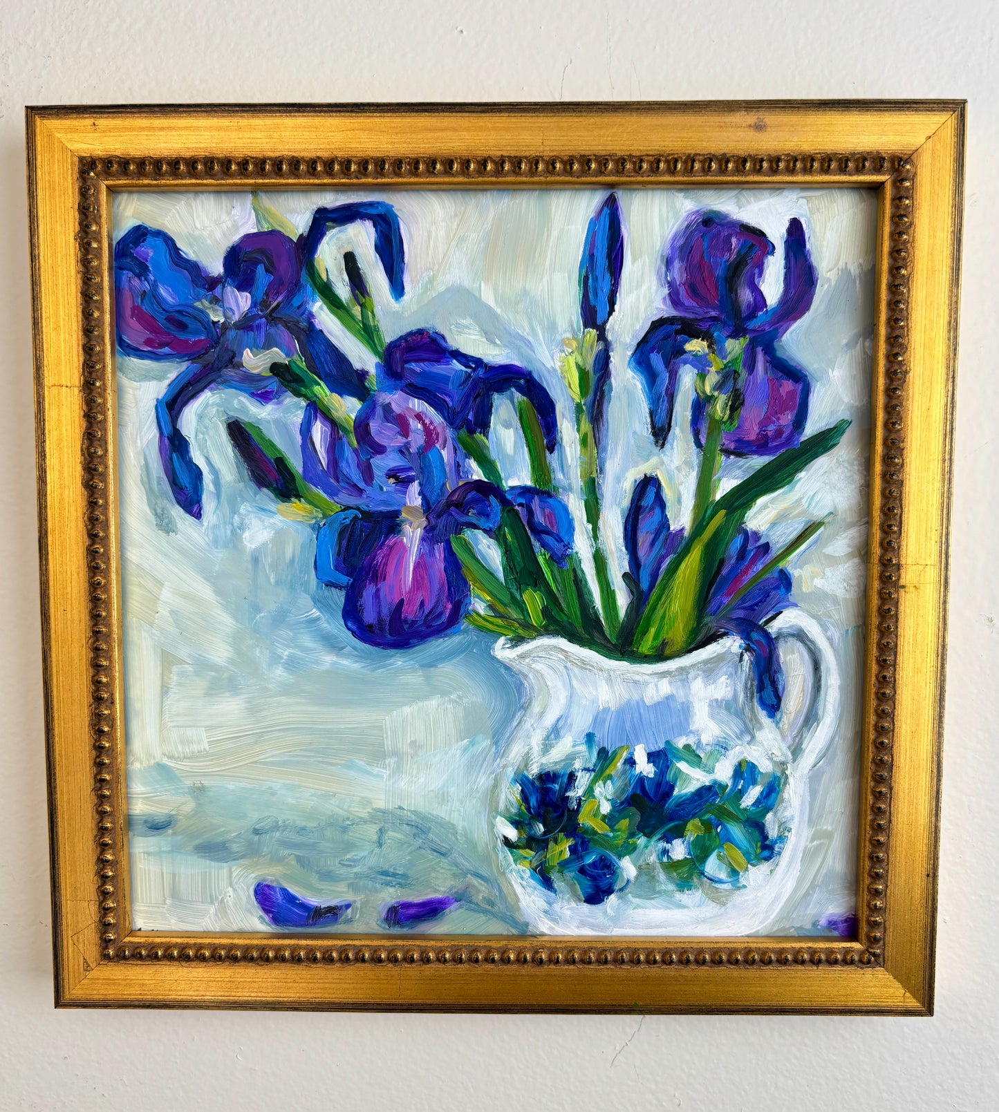 Catherine Husek Mother’s Day framed art features purple irises in a white vase with scattered petals on a light background.