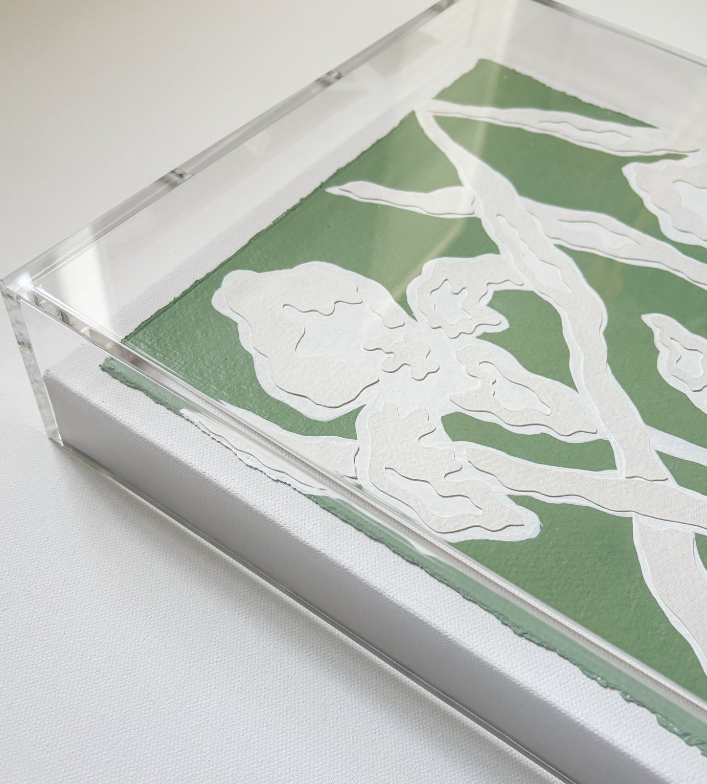 A green and white botanical collage by Kendal Blanchard Art on cotton rag paper in an acrylic box frame.