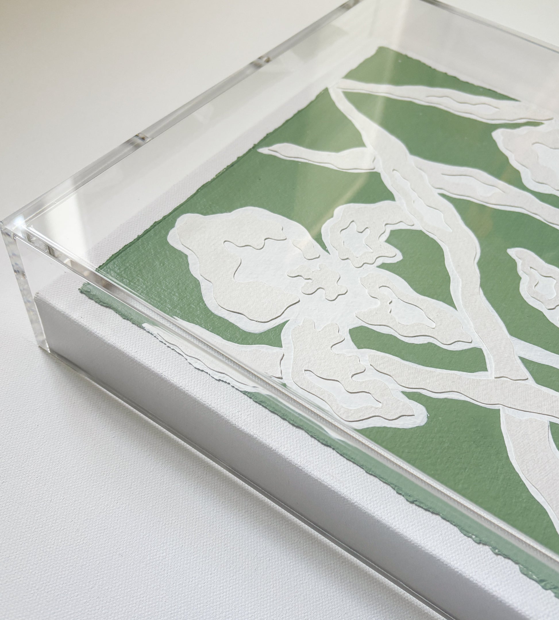 A green and white botanical collage by Kendal Blanchard Art on cotton rag paper in an acrylic box frame.
