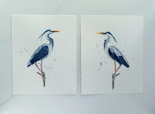 Two watercolor Great Blue Heron paintings of birds standing on branches, facing each other.