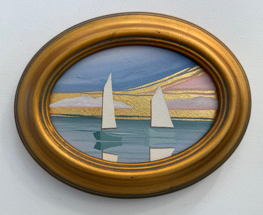 Oval coastal artwork of two sailboats on water at sunset in a gold frame.