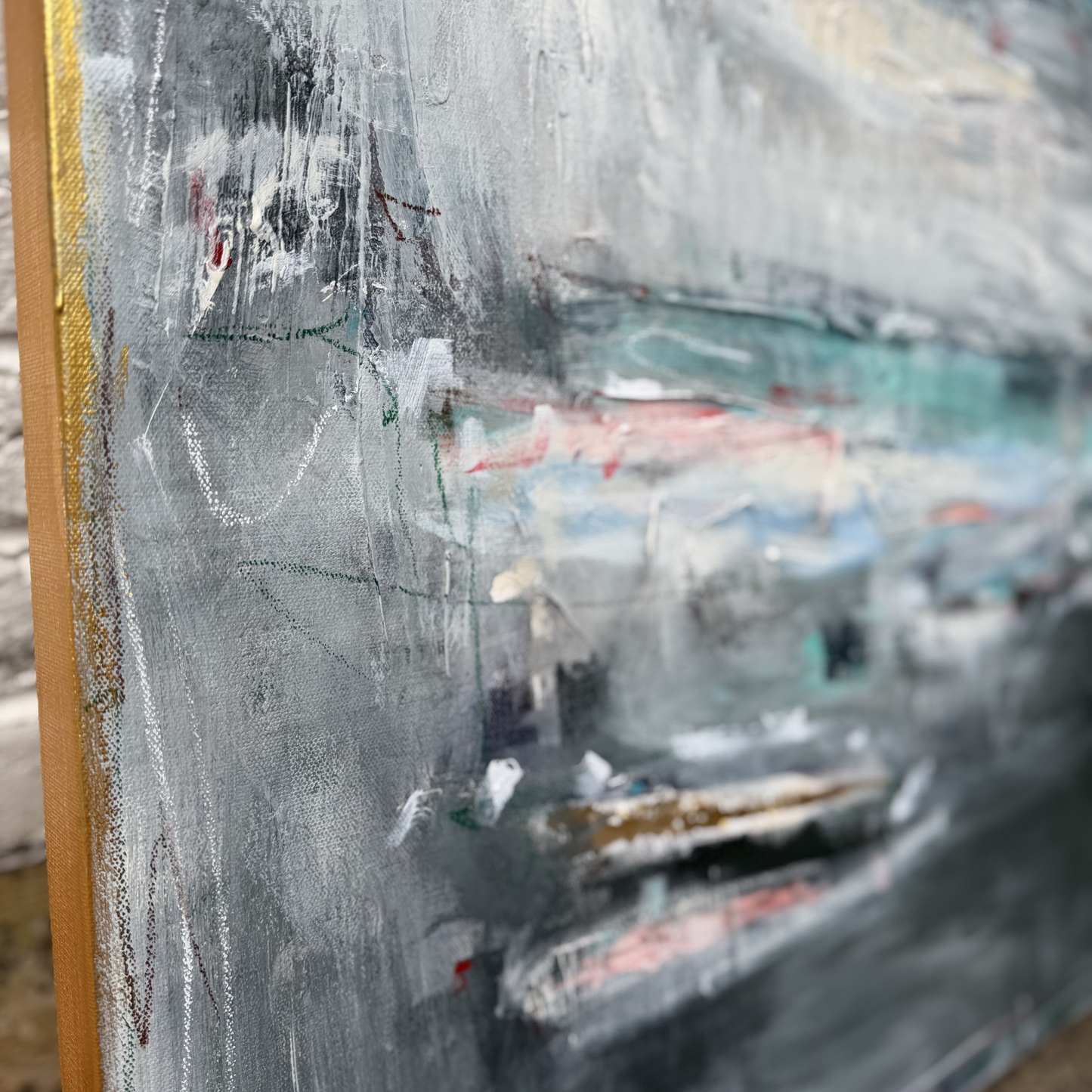 Close-up of a Megan Guidry abstract painting with textured gray, white, and blue over red and green brushstrokes.