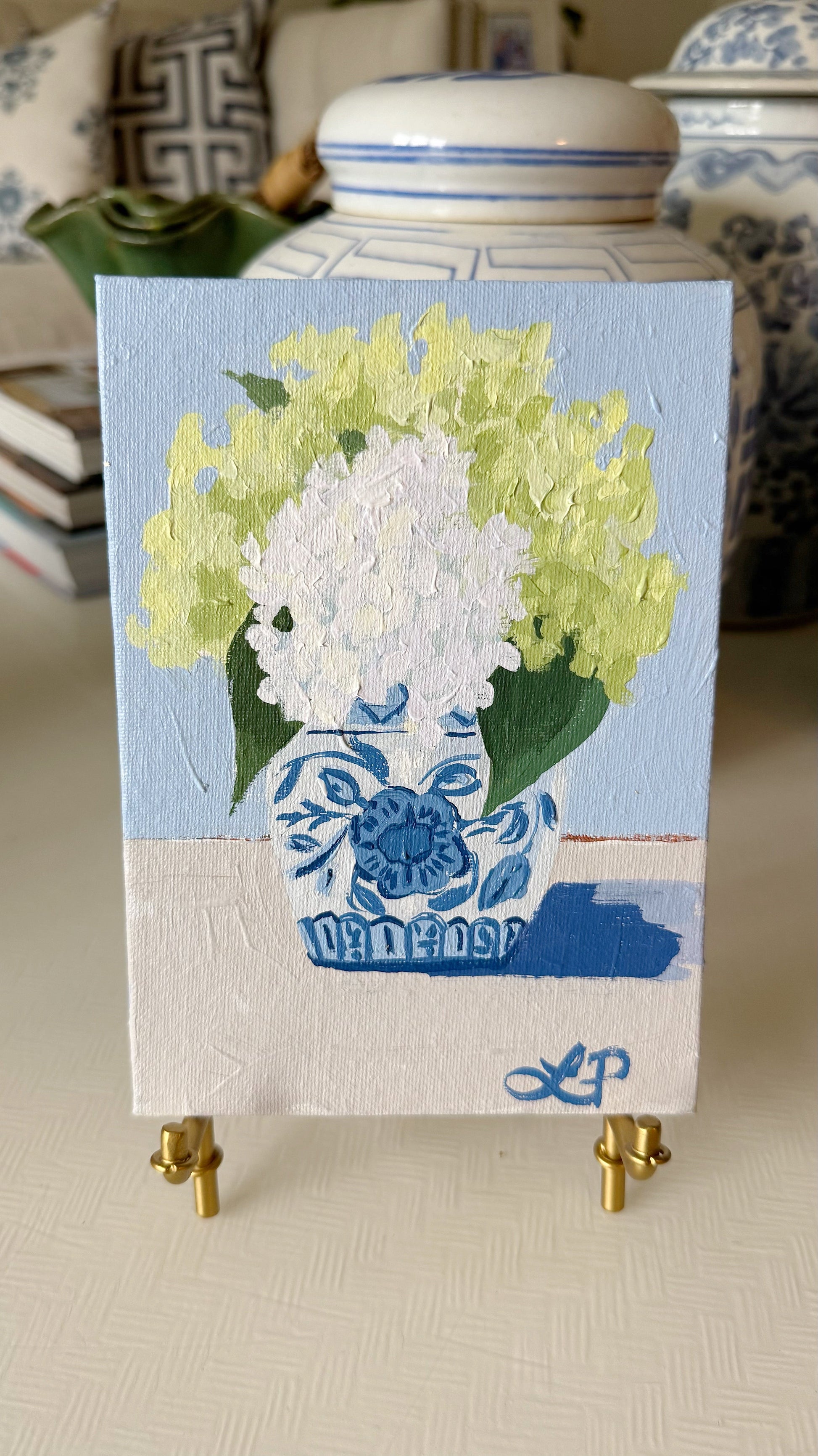Lauri Prins original acrylic painting of white and green hydrangeas in a blue and white vase on gold easel.