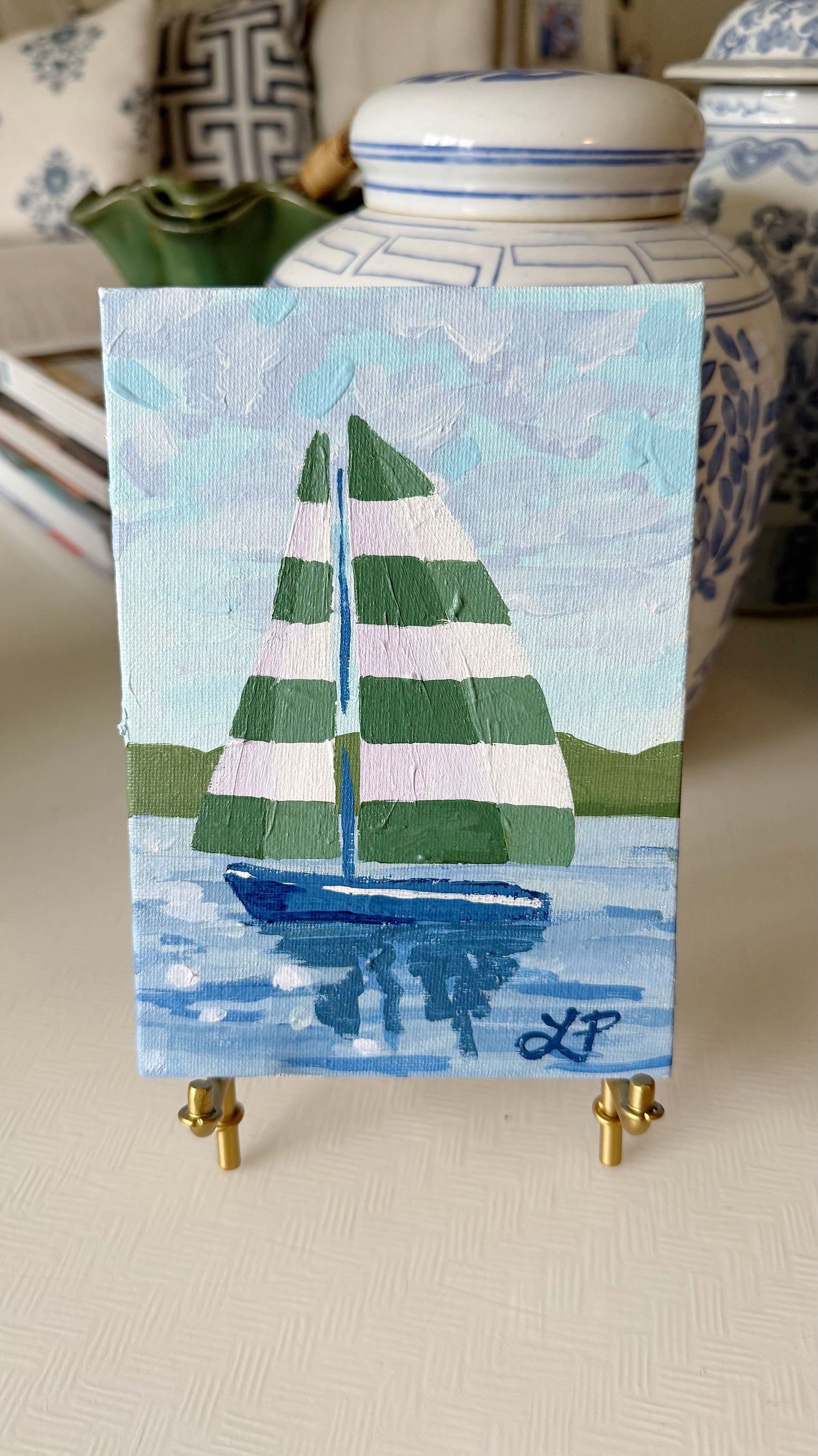 Lauri Prins original acrylic art: sailboat with green & white sails on canvas board, mini easel, blue vases backdrop.