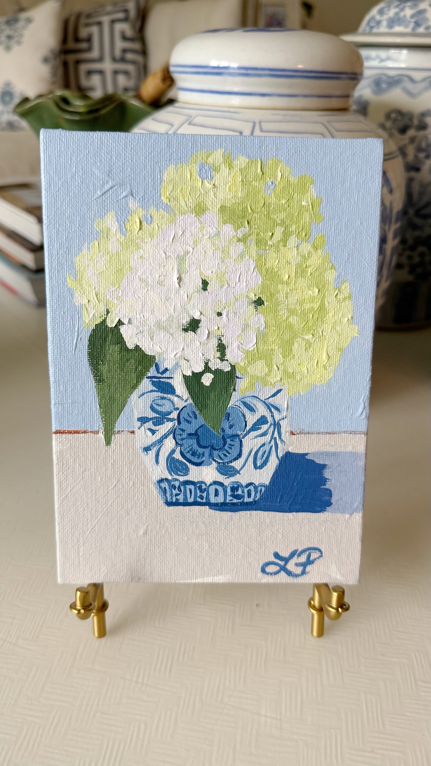 Lauri Prins original acrylic painting of white and pale green hydrangeas in a blue vase on a mini easel.