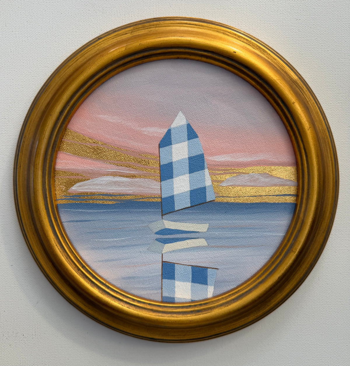 A round 24K goldleaf painting of a checkered sailboat on water under a sunset sky, framed in gold.