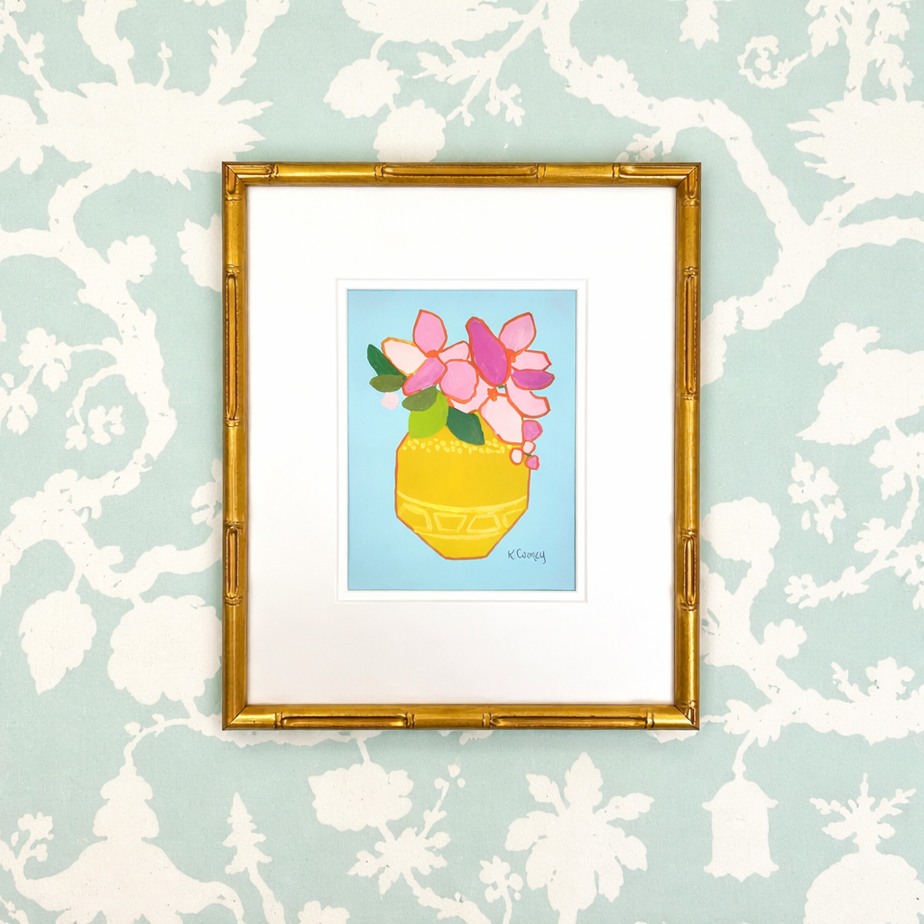 Kristin Cooney Studio framed chinoiserie art of pink flowers in a yellow vase on blue floral wallpaper.
