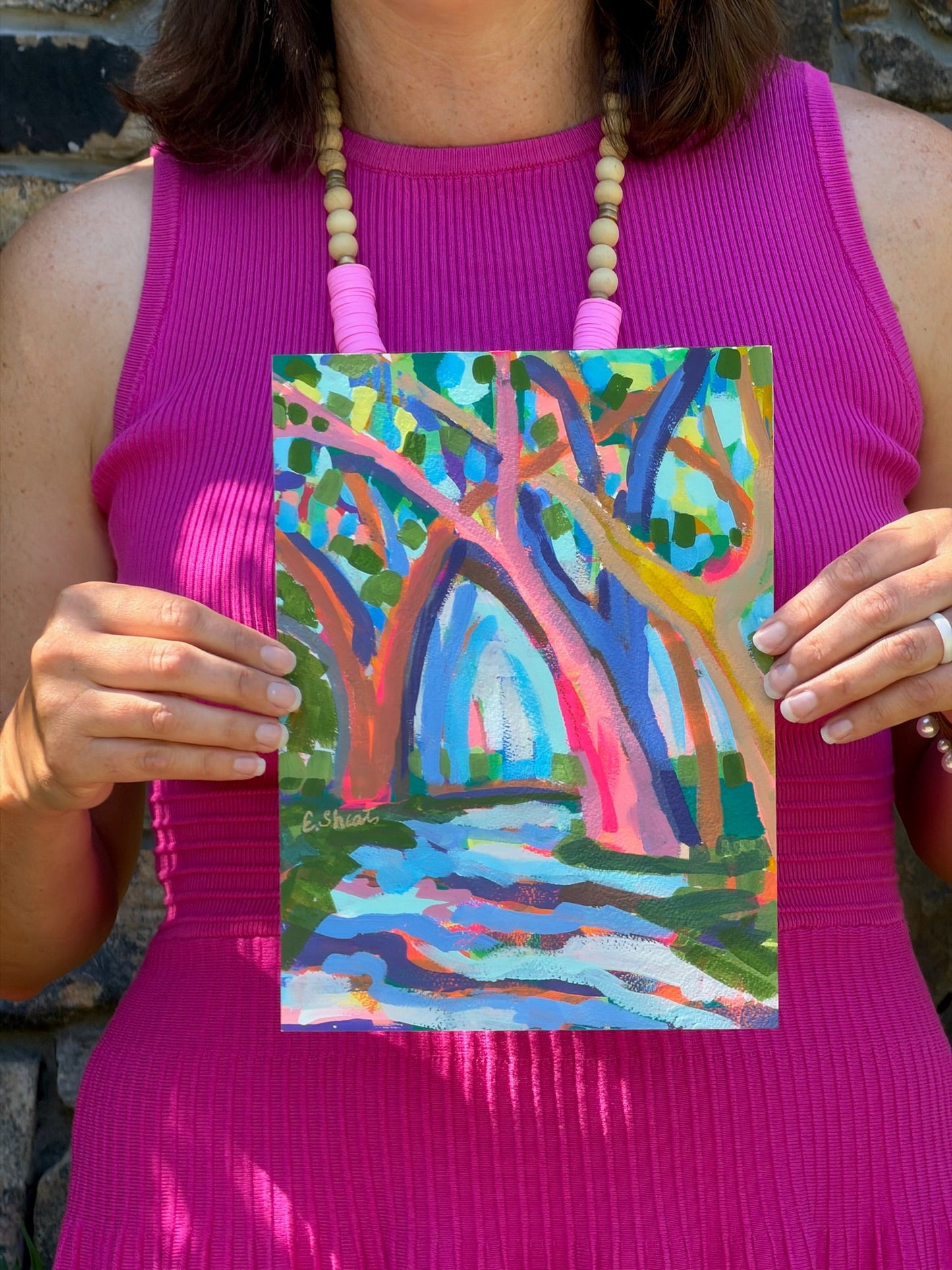 Woman in a pink dress holds an original abstract tree painting by Elizabeth Sheats Art & Design.