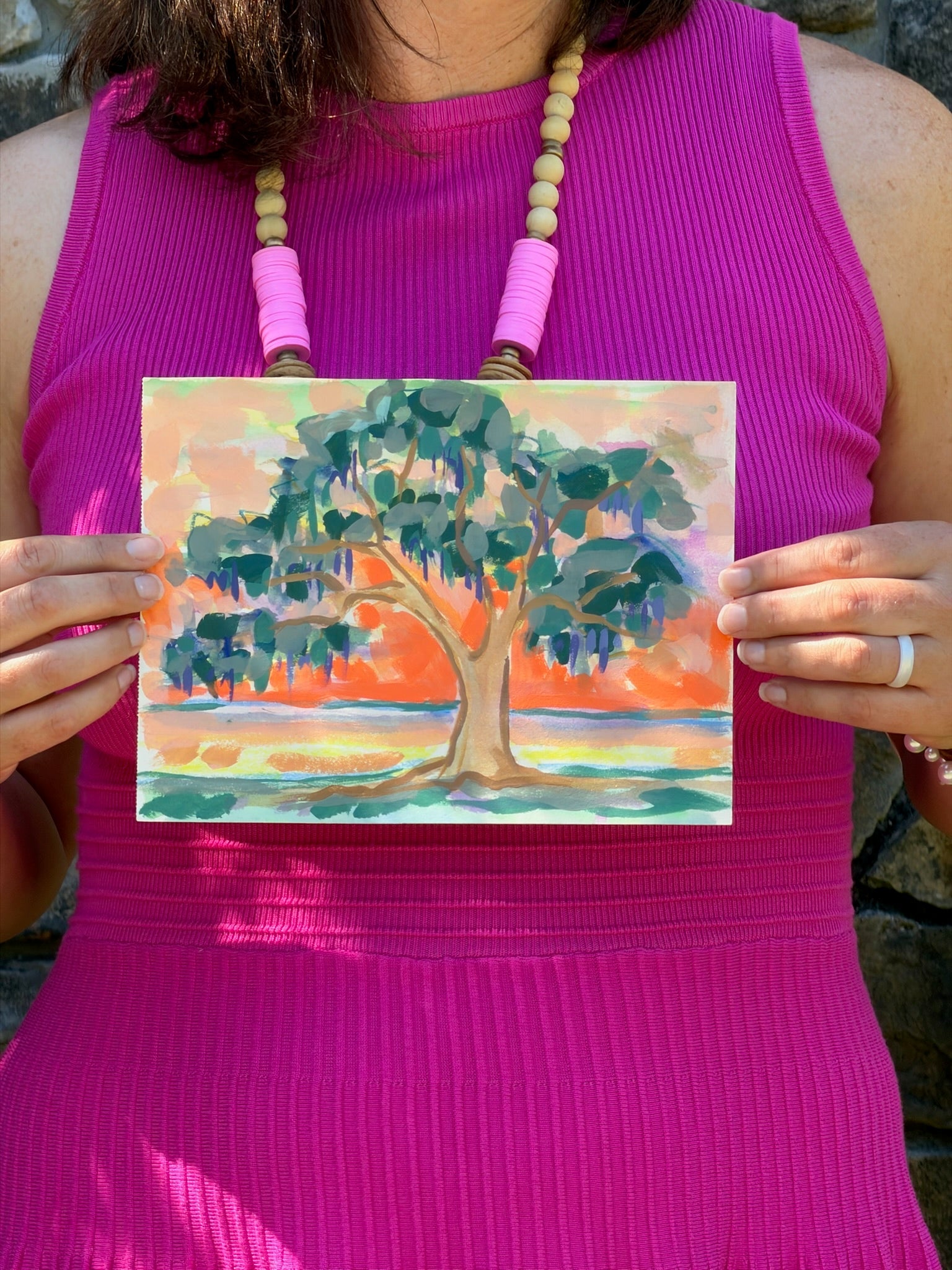A person in a pink dress holds an original watercolor tree art from Elizabeth Sheats Art & Design.