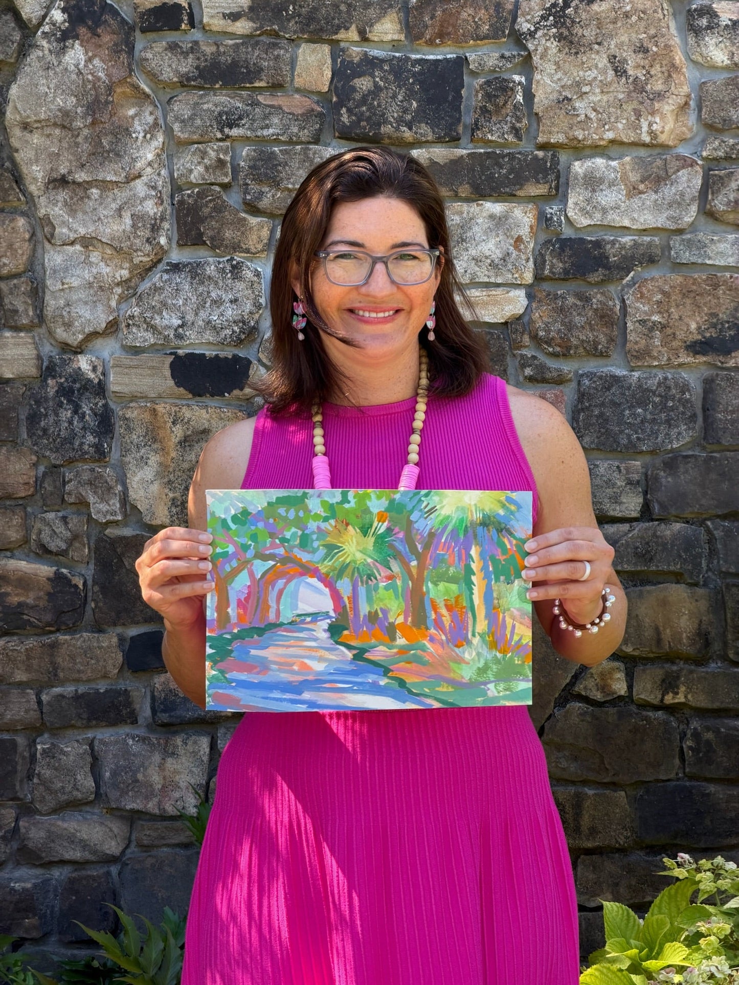 Woman in bright pink dress holds original leafy watercolor art by Elizabeth Sheats Art & Design.