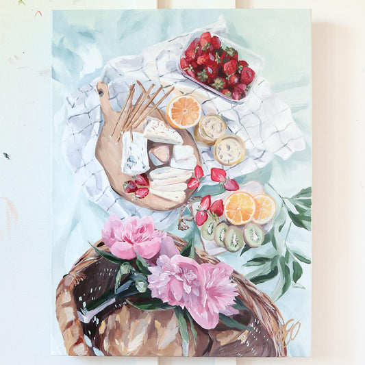 Elizabeth Alice acrylic on canvas: picnic scene with cheese, fruit, flowers & bread on a blanket, viewed from above.