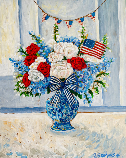 A Lauren Marshall Fine Art blue vase with patriotic flowers, bow, and flag—ideal Fourth of July decor.