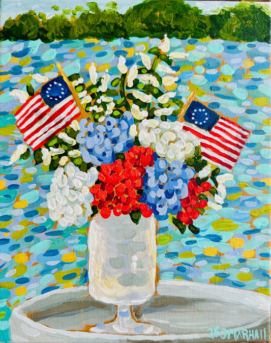 Lauren Marshall Fine Art patriotic wall decor with a vase of red, white, blue flowers and flags by a lakeside.