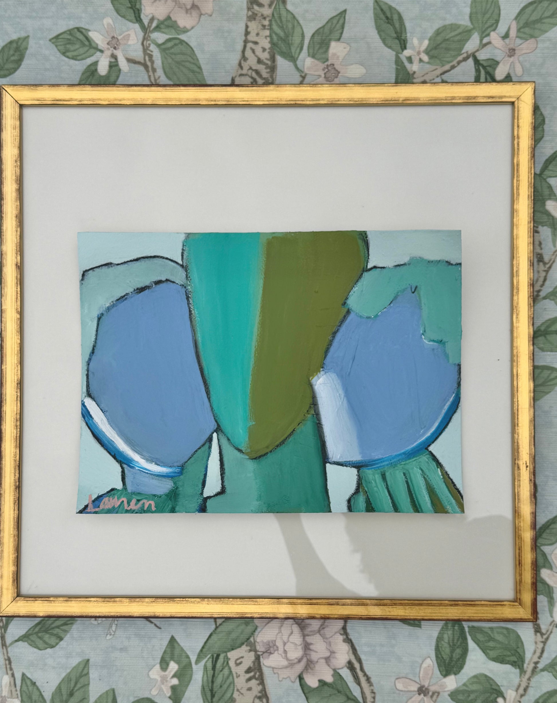 KP Art Collective mixed media in blue and green, gold-framed, shown on floral-patterned wallpaper.