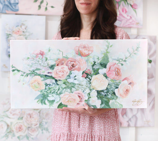 Woman in a pink dress holds an Elizabeth Alice acrylic painting of pink roses and white flowers on canvas.