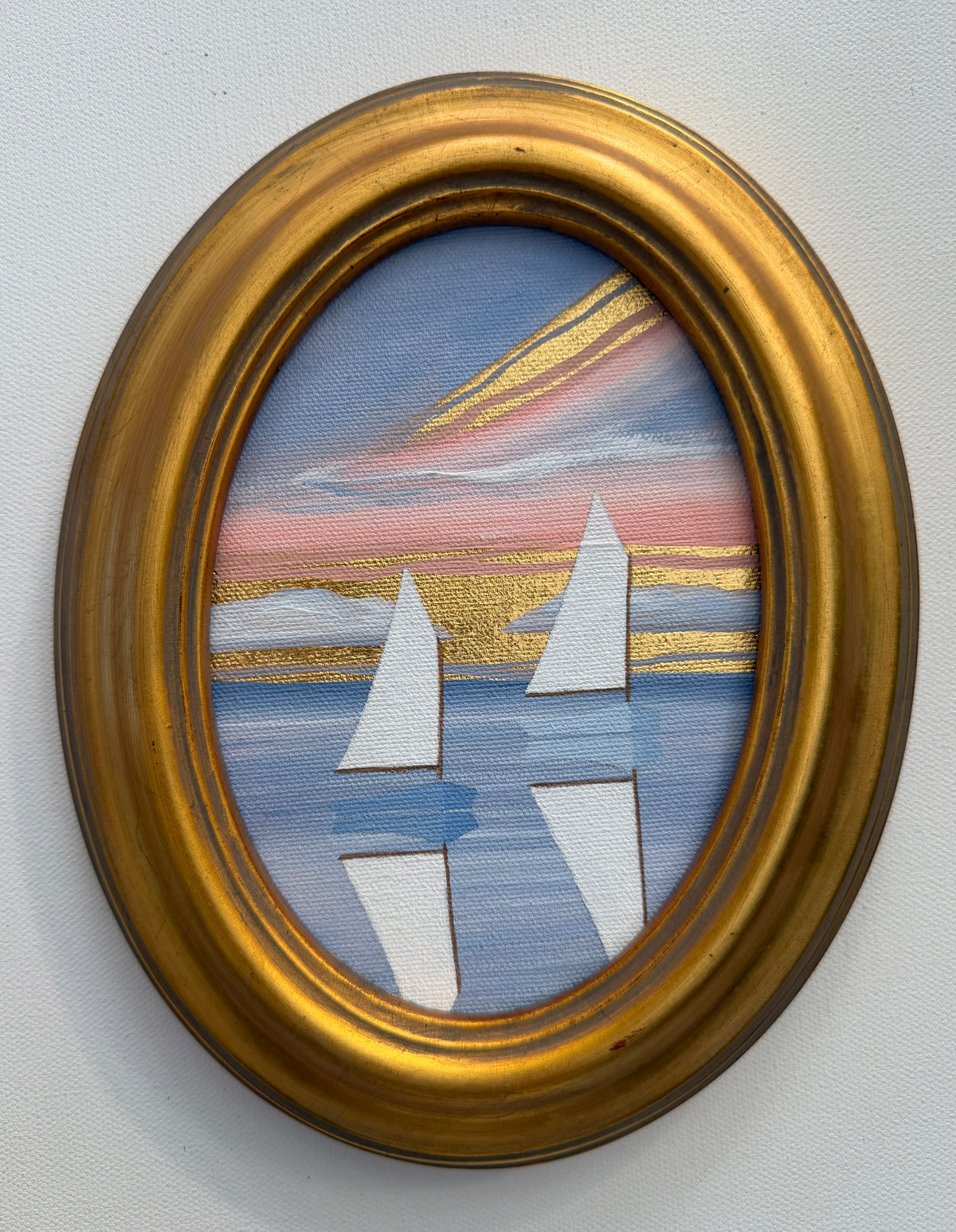 Two sailboats drift on water at sunset, presented as Nikki Storer coastal artwork in an ornate gold oval frame.