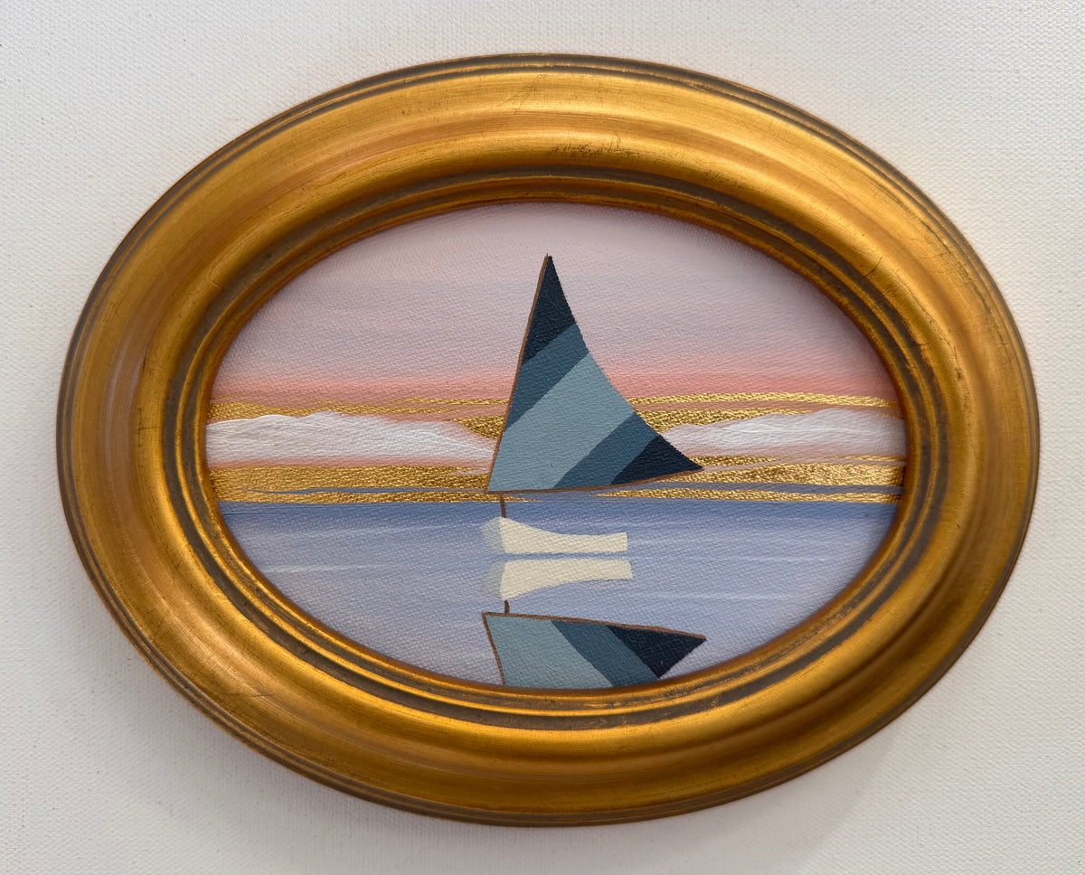 A Nikki Storer coastal painting of a sailboat on calm water at sunset, set in an oval gold frame.