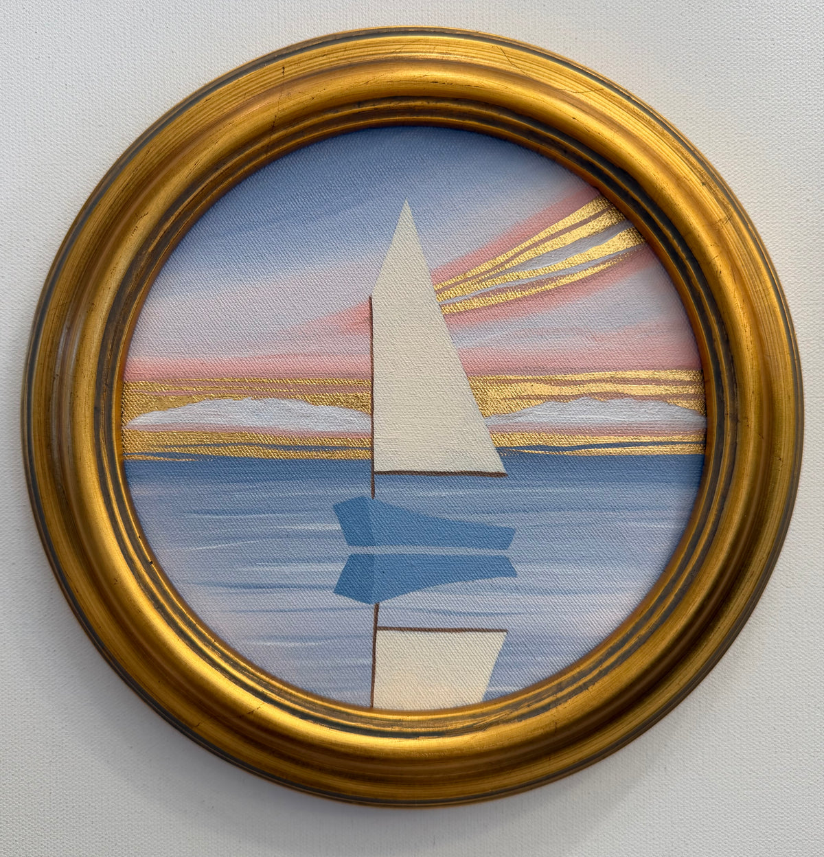 A circular 24K goldleaf painting of a minimalist sailboat on water beneath a pink and gold sunset.