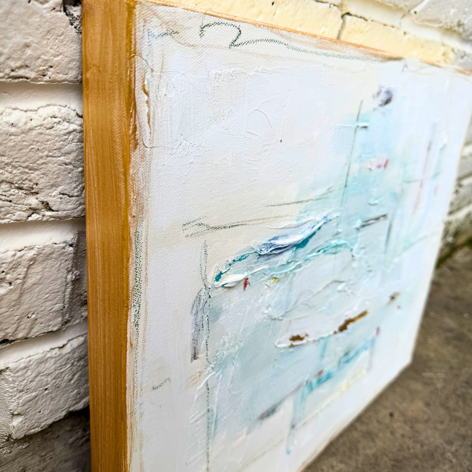 Close-up of a Megan Guidry abstract painting in glacial blue hues, leaning against a white brick wall.