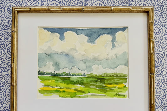 Framed watercolor painting of a landscape with green fields and blue sky.