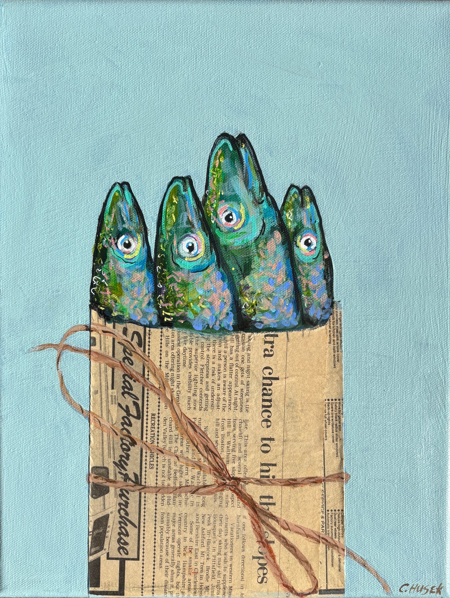 Four painted fish heads by Catherine Husek evoke playful coastal art on a light blue, newspaper-wrapped background.