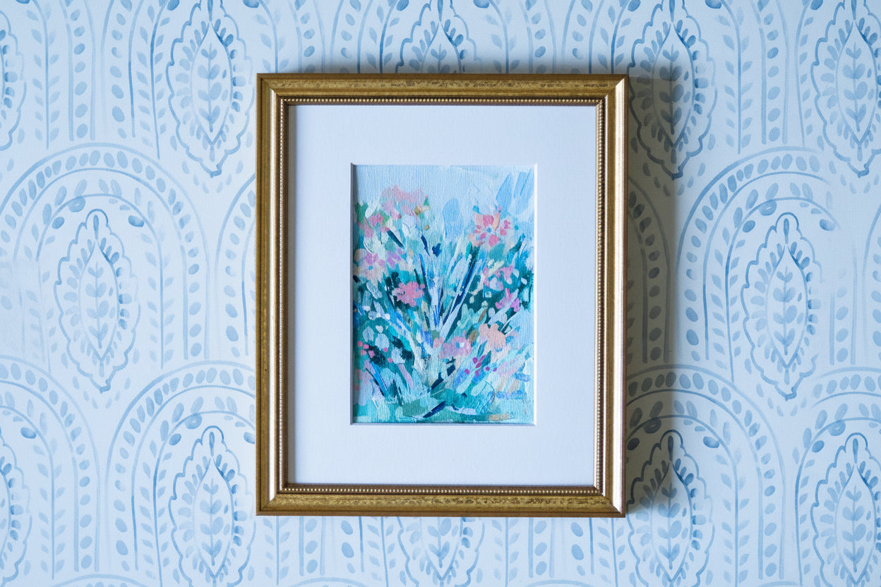 Framed artwork with floral design on a blue patterned wall